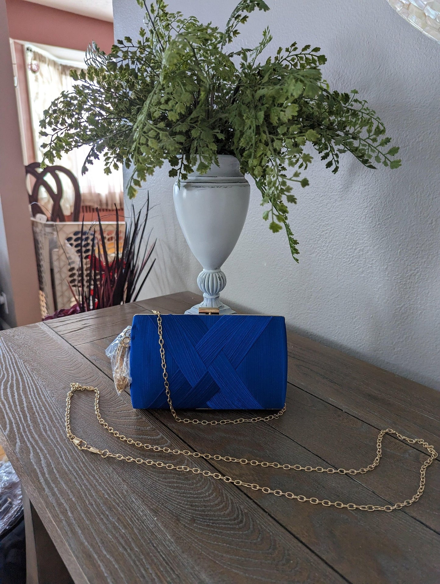 Blue chain handle clutch with dual chains and diagonal design displayed on a wooden table.