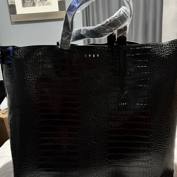 Crocodile 1989 print black tote bag with textured design and spacious interior.