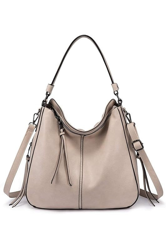 Vegan leather hobo handbag in taupe with gun black hardware, tassels, and adjustable strap.